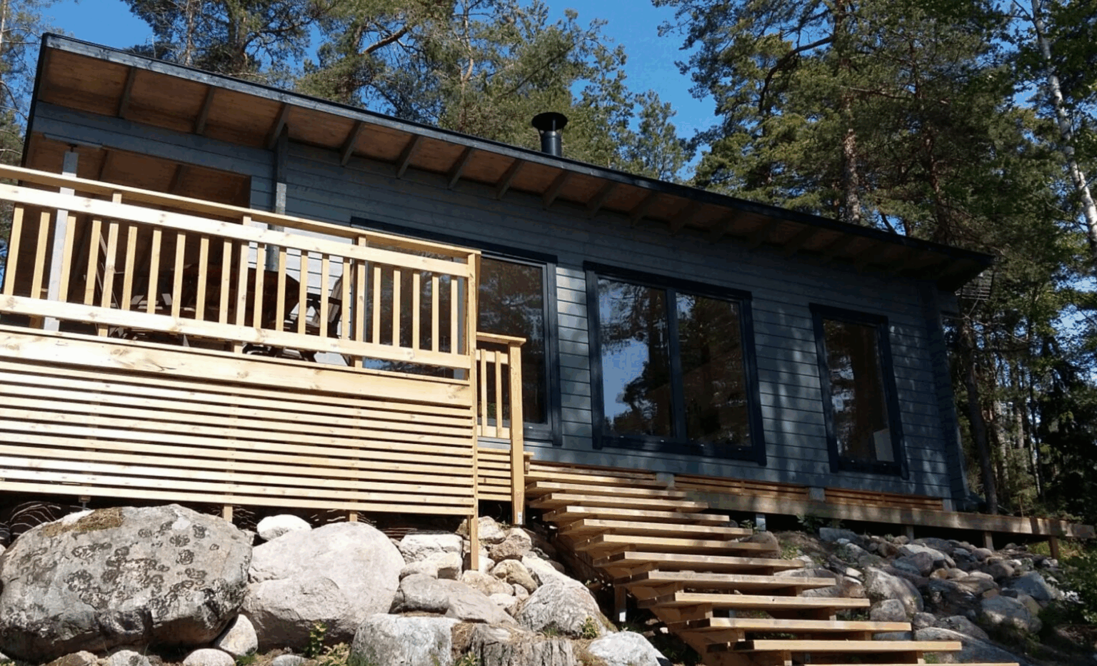 Terassilla varustettu hirsimökki auringonpaisteessa